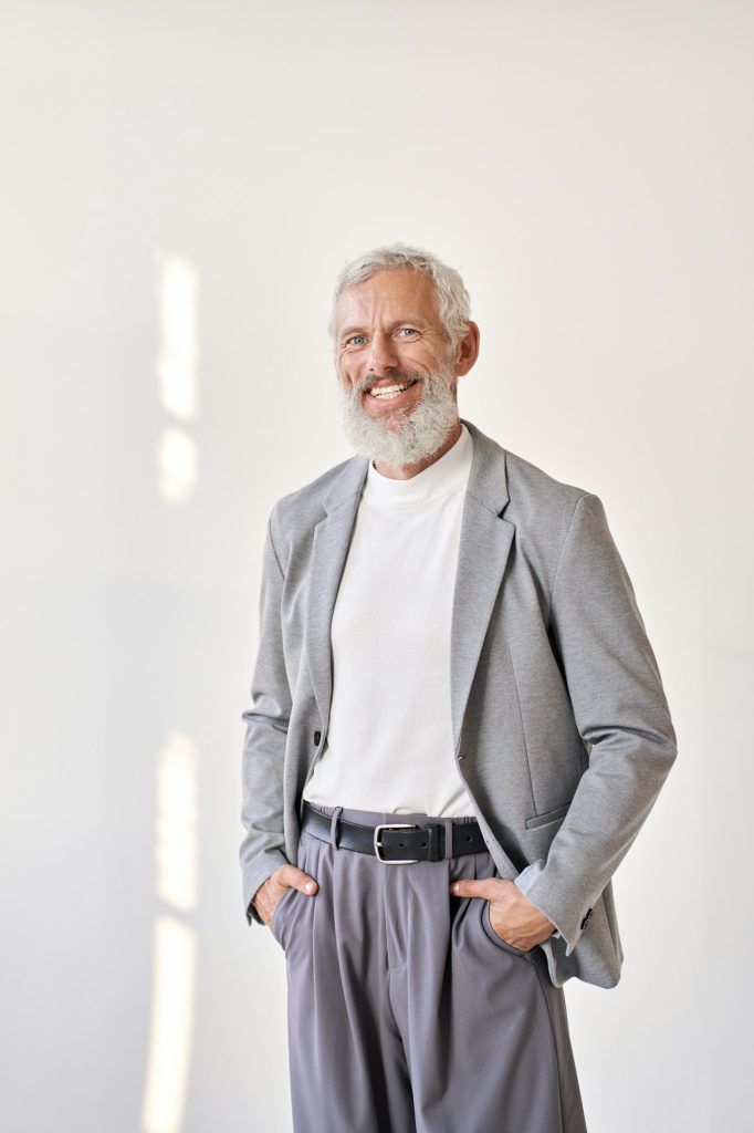 Smiling mature older business man isolated on white, vertical portrait.